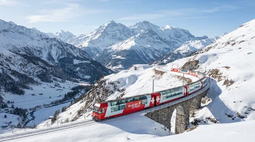 A glass-roofed train winding through the snowy Swiss Alps.